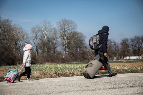 Adult and child holding suitcases and walking